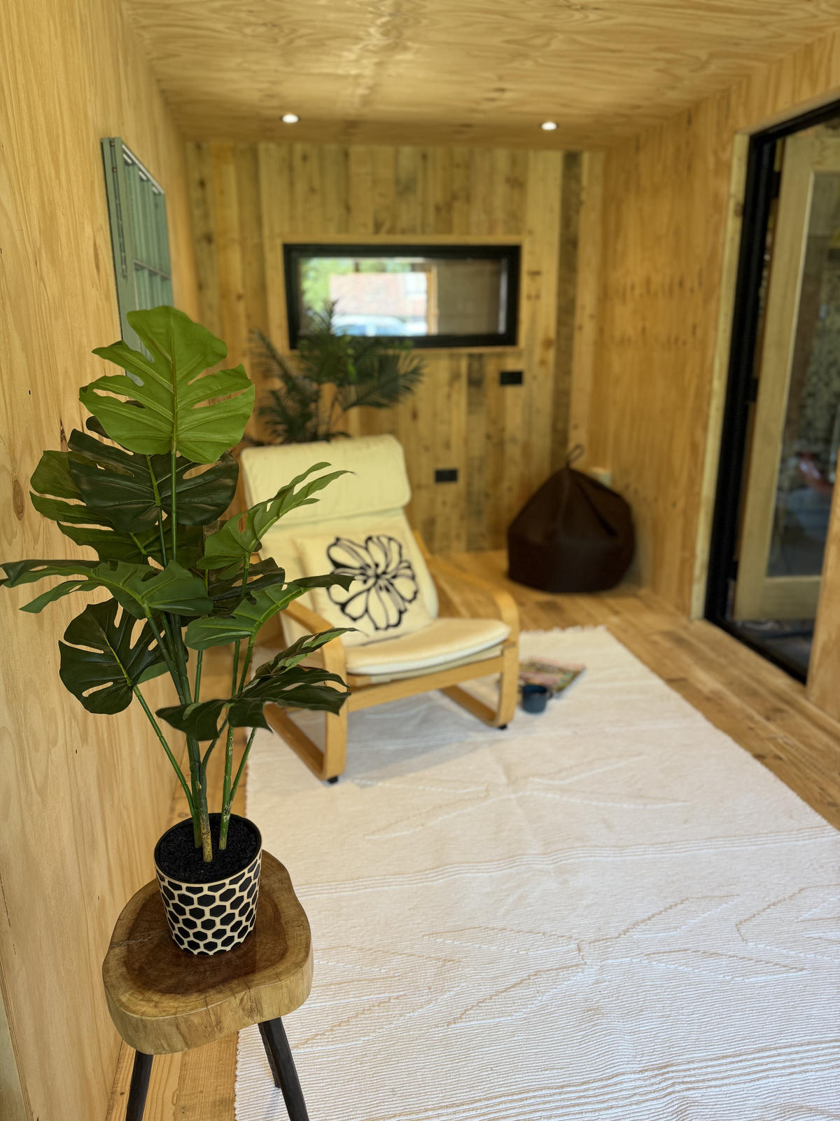 Corva interior — monstera plant with armchair and reading space beyond