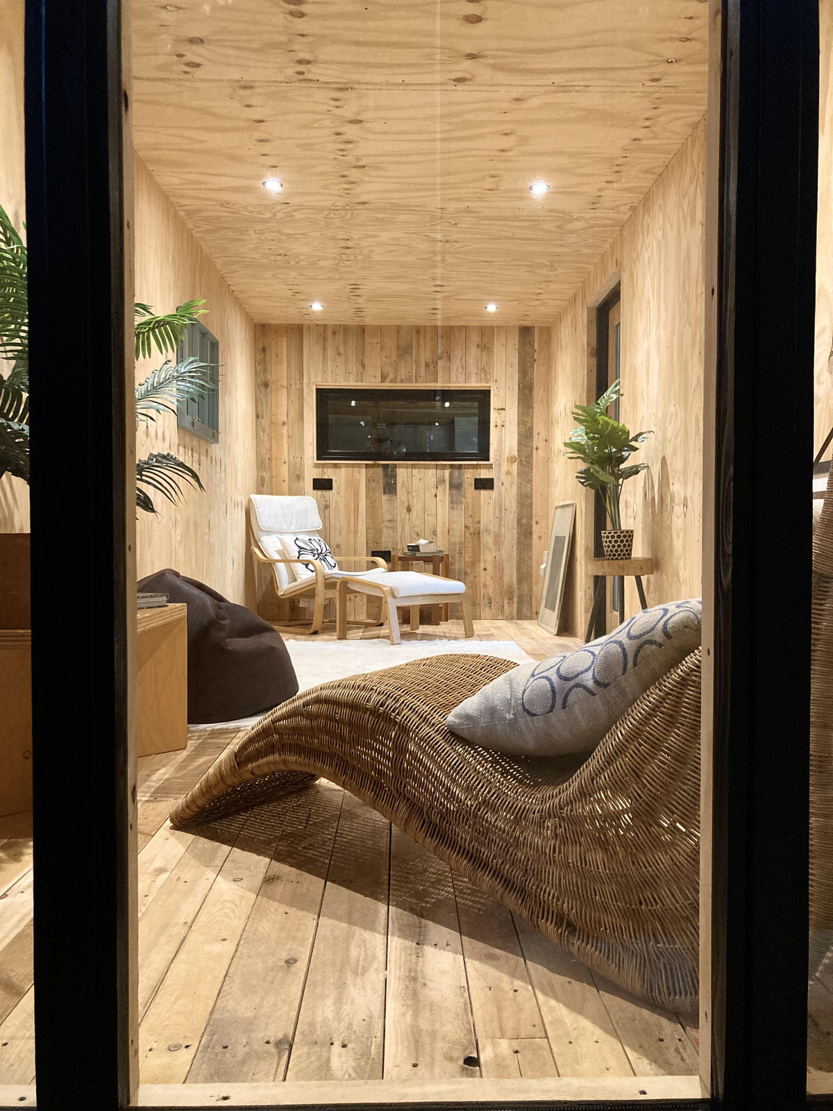 Corva interior — living space viewed through the glazed doors, wicker chaise and armchair