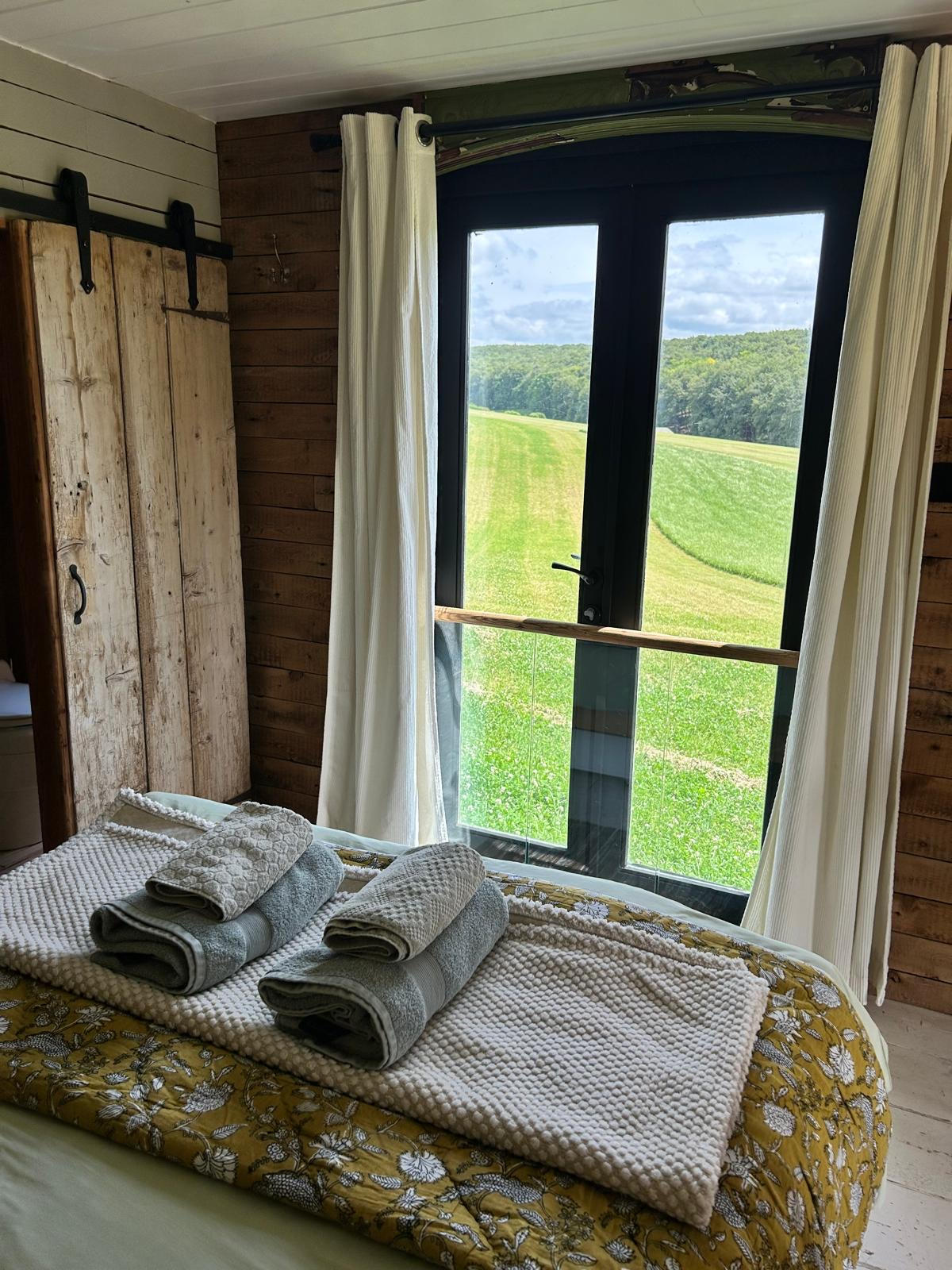 Kalou cabin bedroom with French doors onto open countryside, near Goodwood Estate